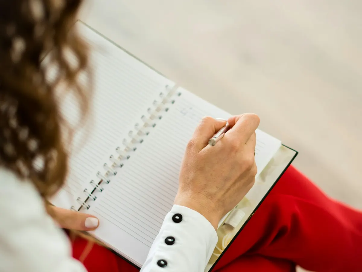 A clinician writing notes in a spiral notebook on her lap