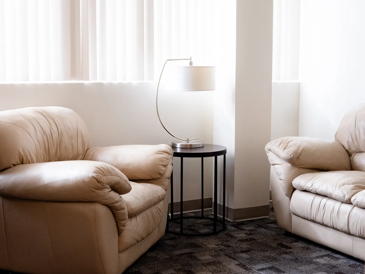 Two leather armchairs and a floor lamp in a sunlit therapy office